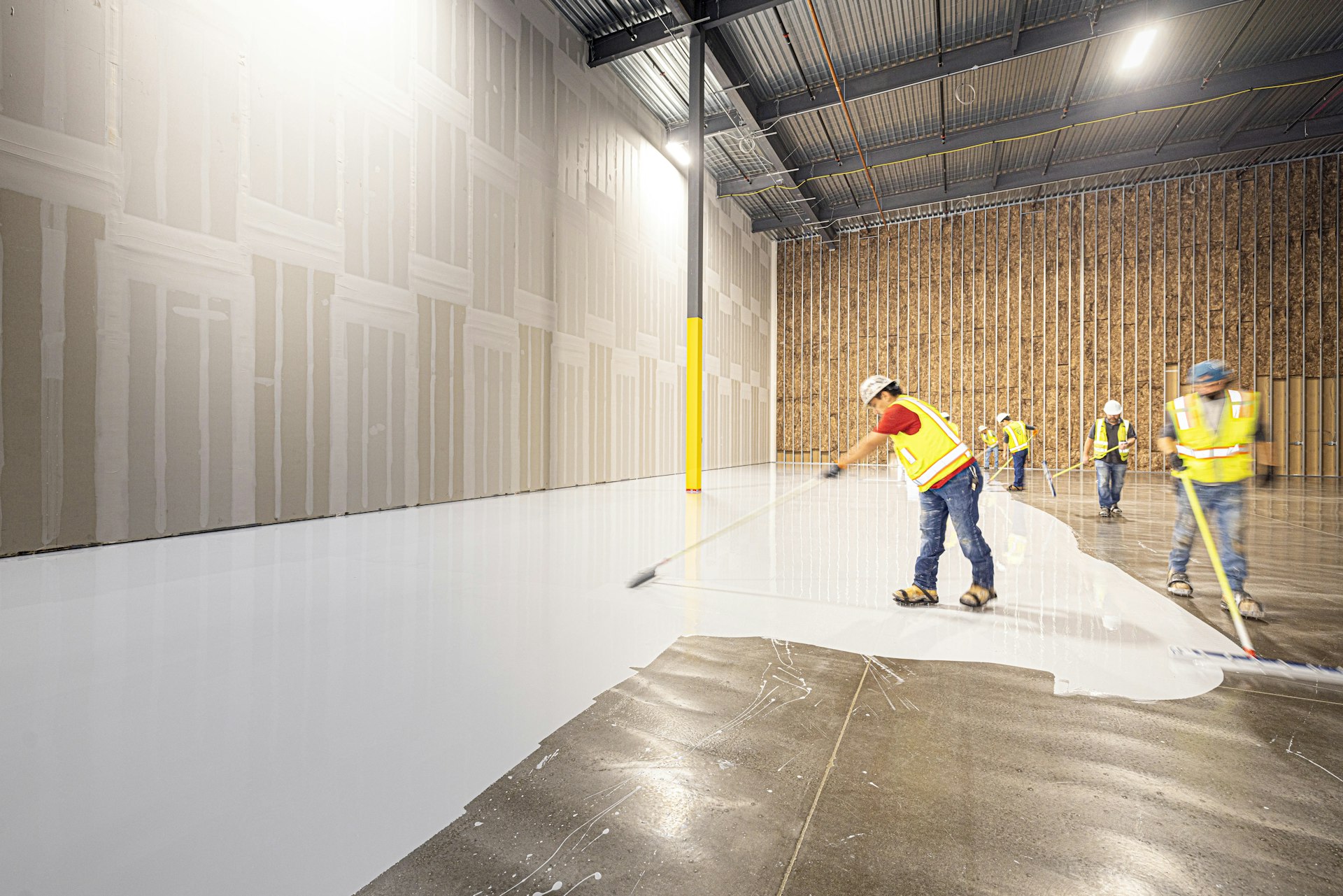 Crew applying a floor coating in a large industrial space